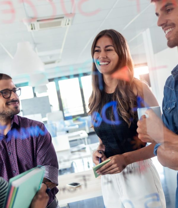 Shot of successful business team discussing together in front of office glass board in the coworking space.